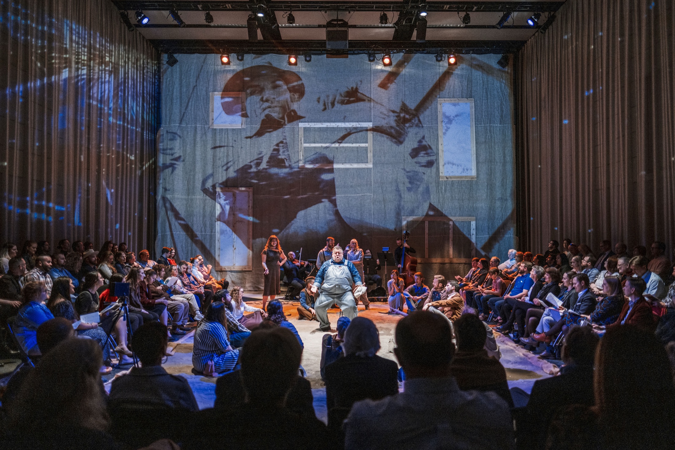 Dust Bowl stage image with surrounding audience and large projection