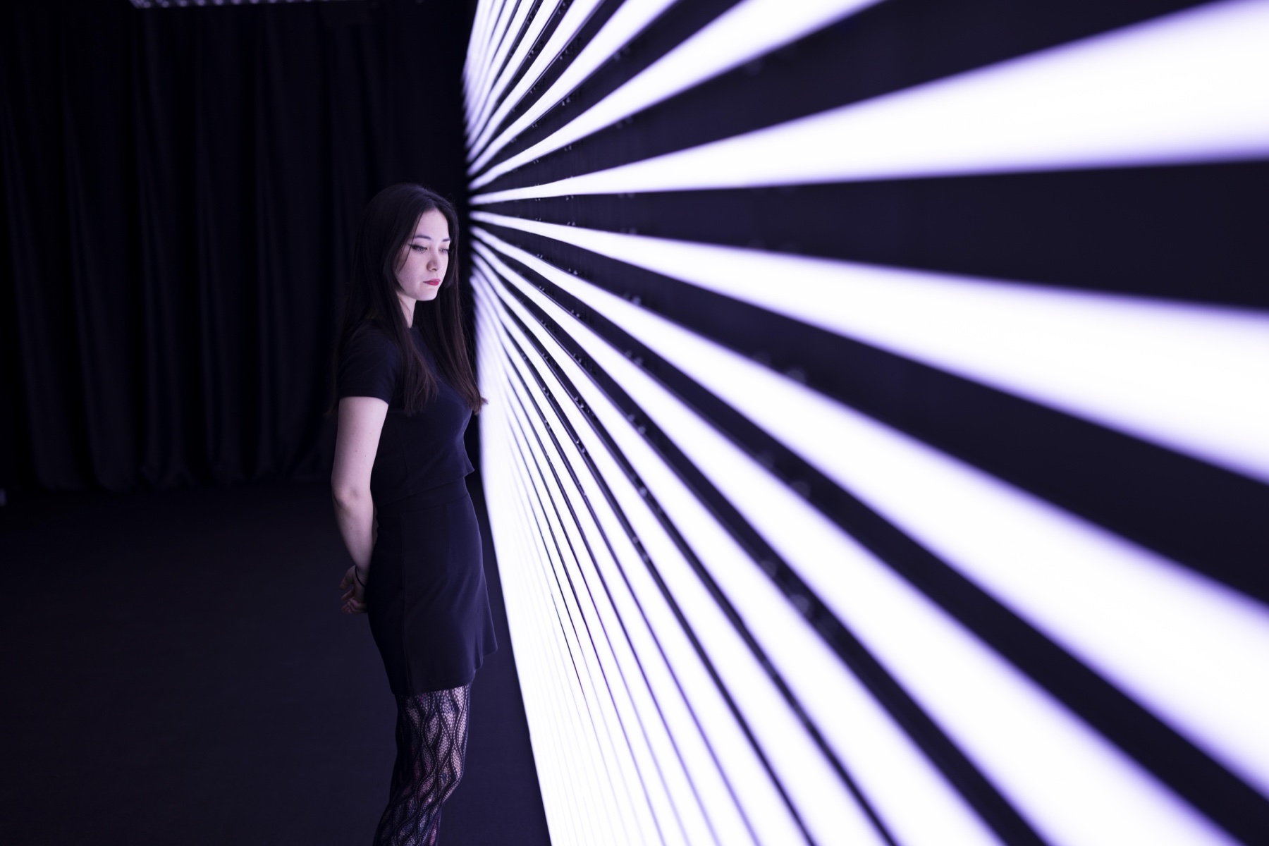 Visitor standing beside ECLIPSE by NONOTAK wall of linear light